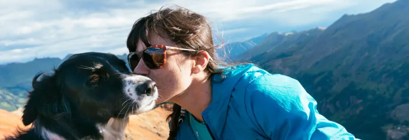 Image of a woman kissing her dog on the cheek. 