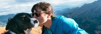 Image of a woman kissing her dog on the cheek. 